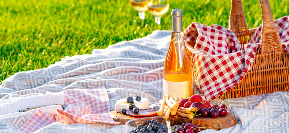 Picnic Setting In A Meadow. Picnic Basket, Wine, Berries, Jamon,