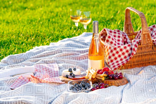 Picnic Setting In A Meadow. Picnic Basket, Wine, Berries, Jamon,
